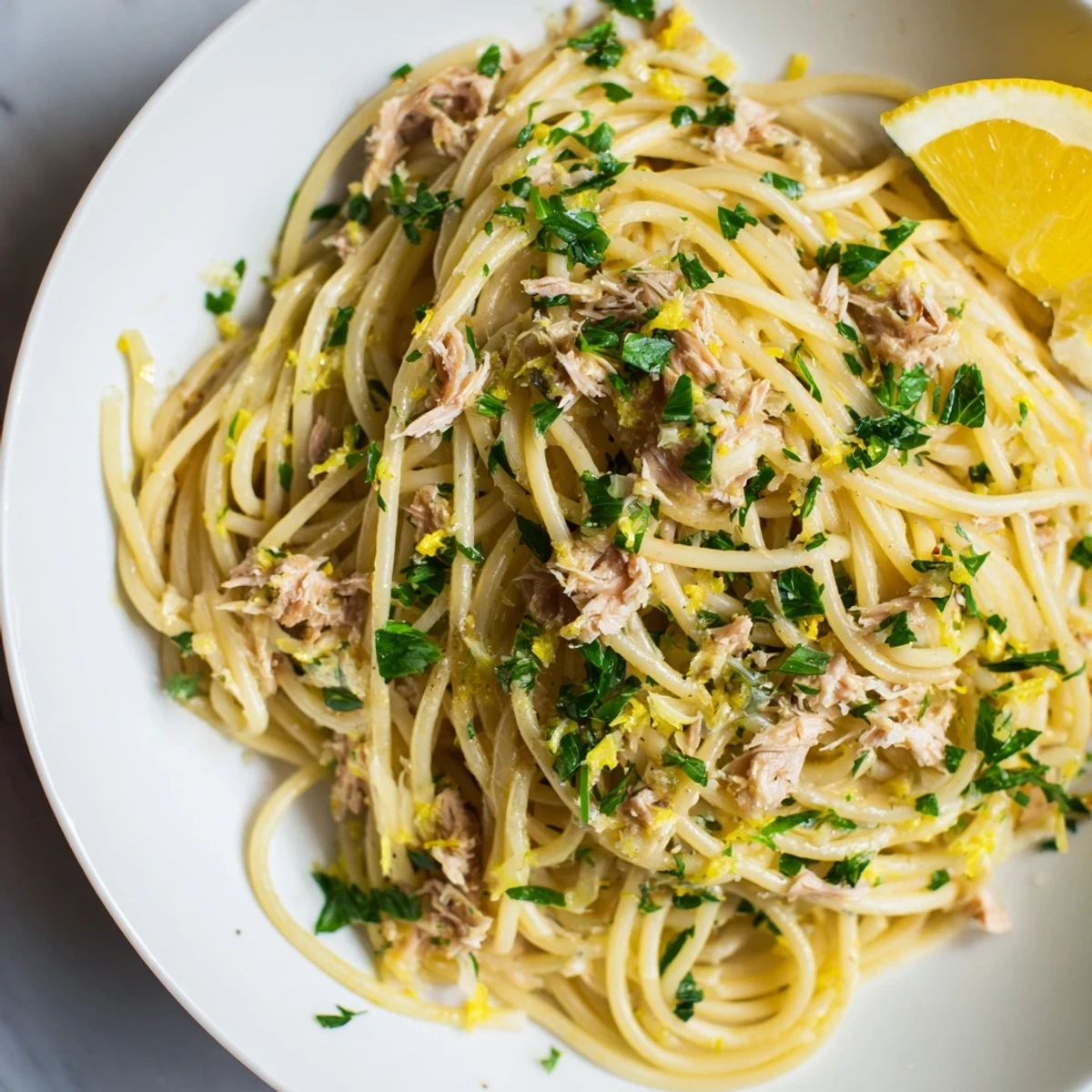 Golden strands of Lemon-Garlic Tuna Spaghetti with flaky tuna and bright lemon slices piled high.
