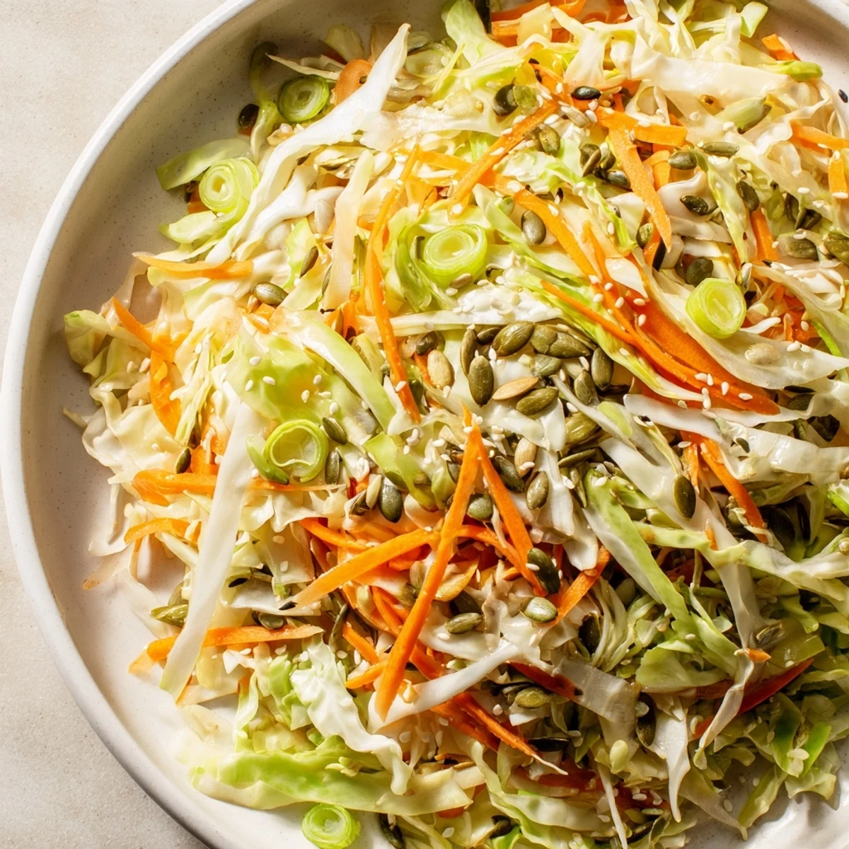 Freshly tossed Cabbage-Core Slaw Salad, featuring vibrant colors of shredded cabbage, carrots, and toasted seeds.