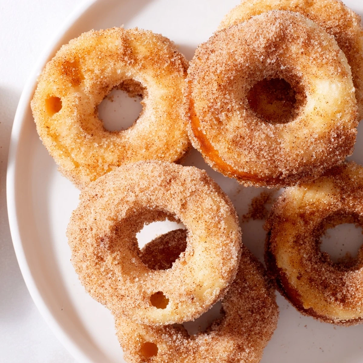 Pile of golden-brown 1-Minute Air Fryer Donuts, coated in cinnamon sugar, making a quick, easy treat.