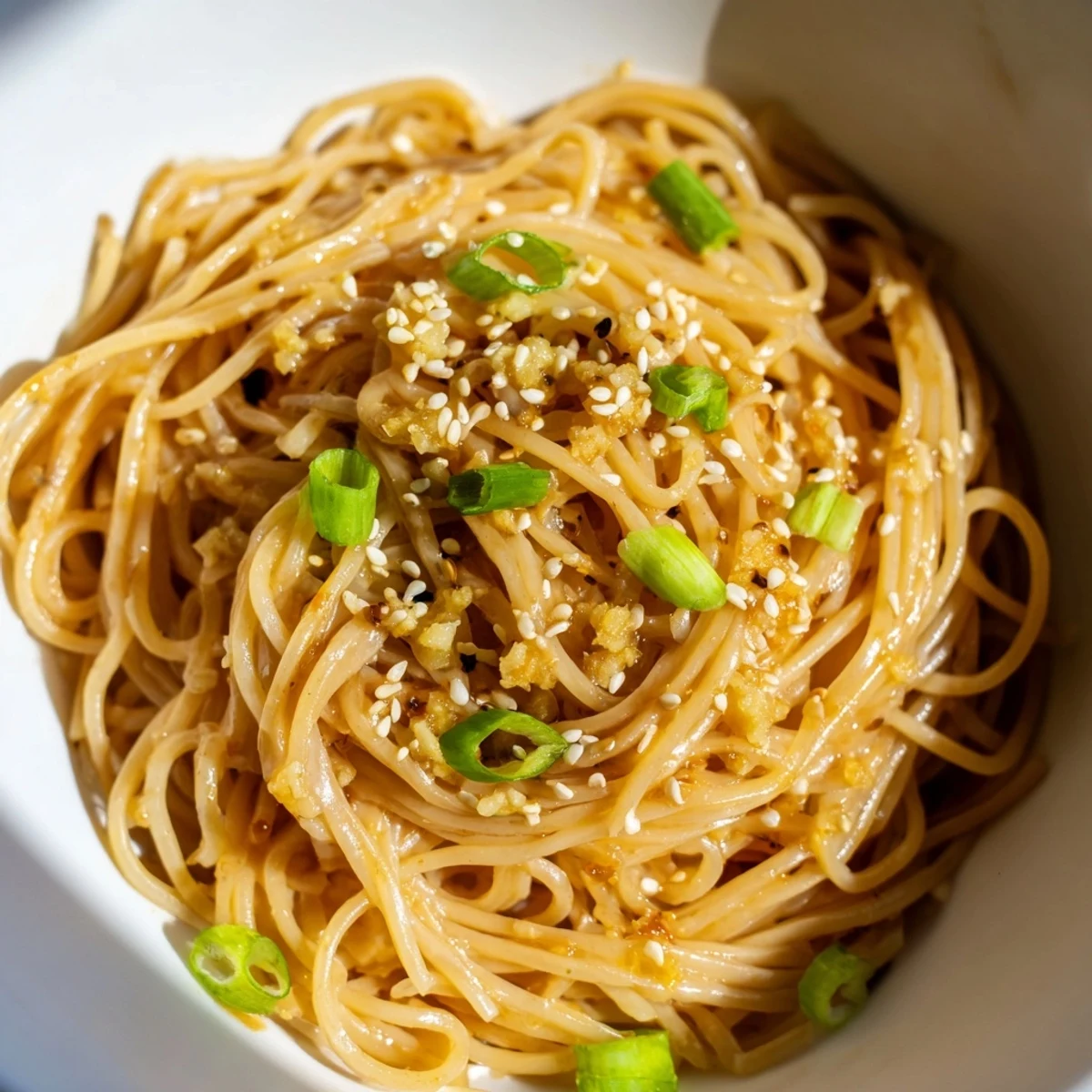 Fork ready to twirl noodles from a vibrant Asian Garlic Noodle Bowl topped with fresh cilantro and bean sprouts.