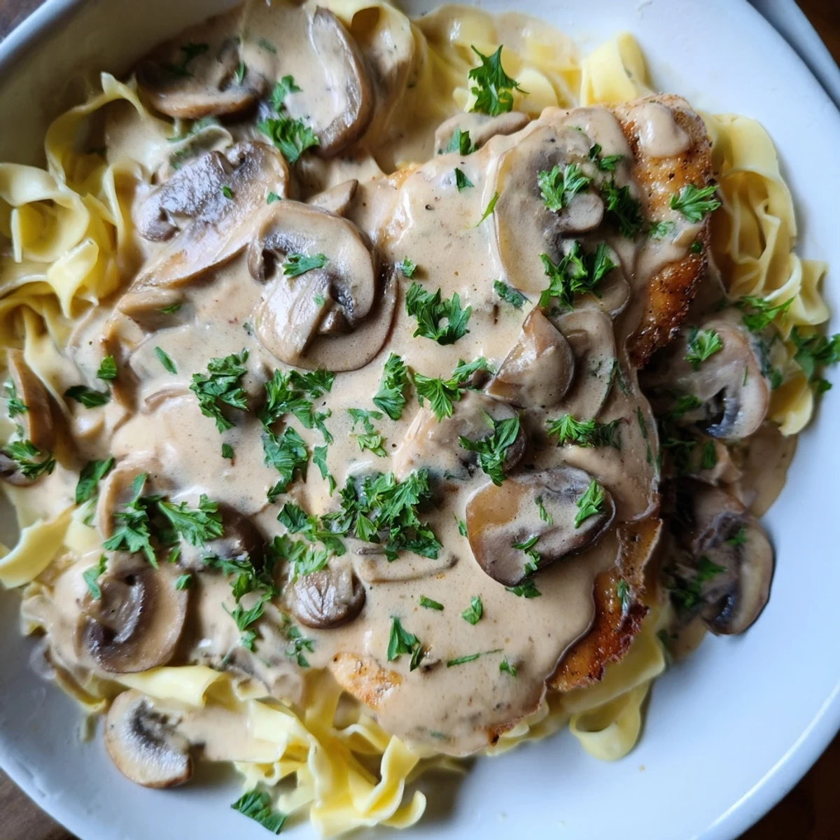Golden-brown pan-seared chicken breasts bathed in a creamy Marsala and mushroom sauce, served over fettuccine for a comforting Italian-American dinner.