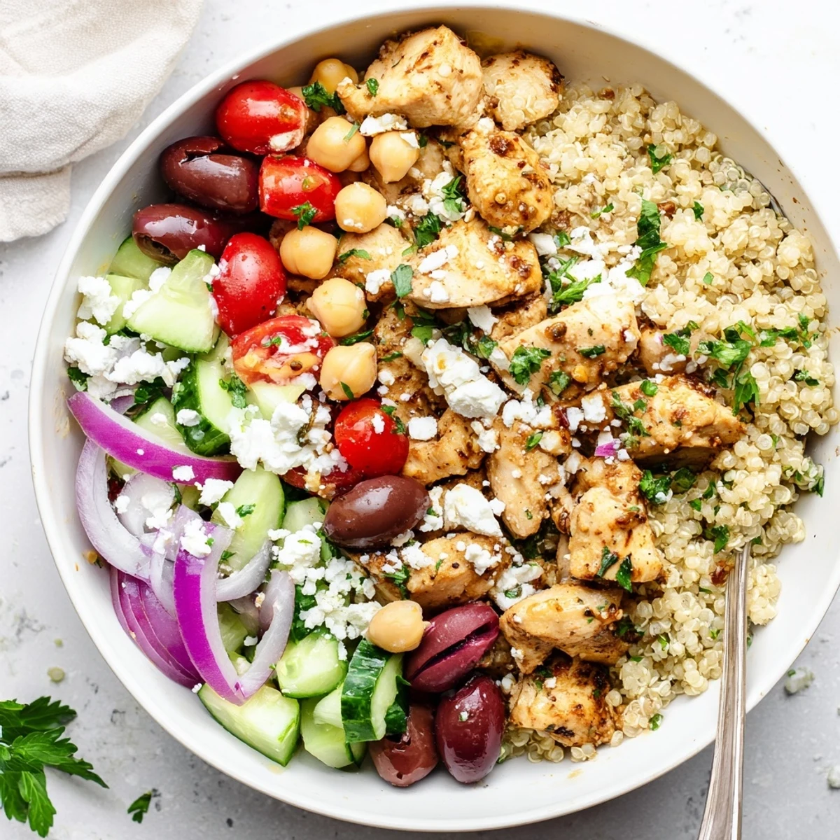 A vibrant Mediterranean Chicken Bowl topped with Kalamata olives, cherry tomatoes, and chickpeas, drizzled with a zesty lemon-oregano dressing.