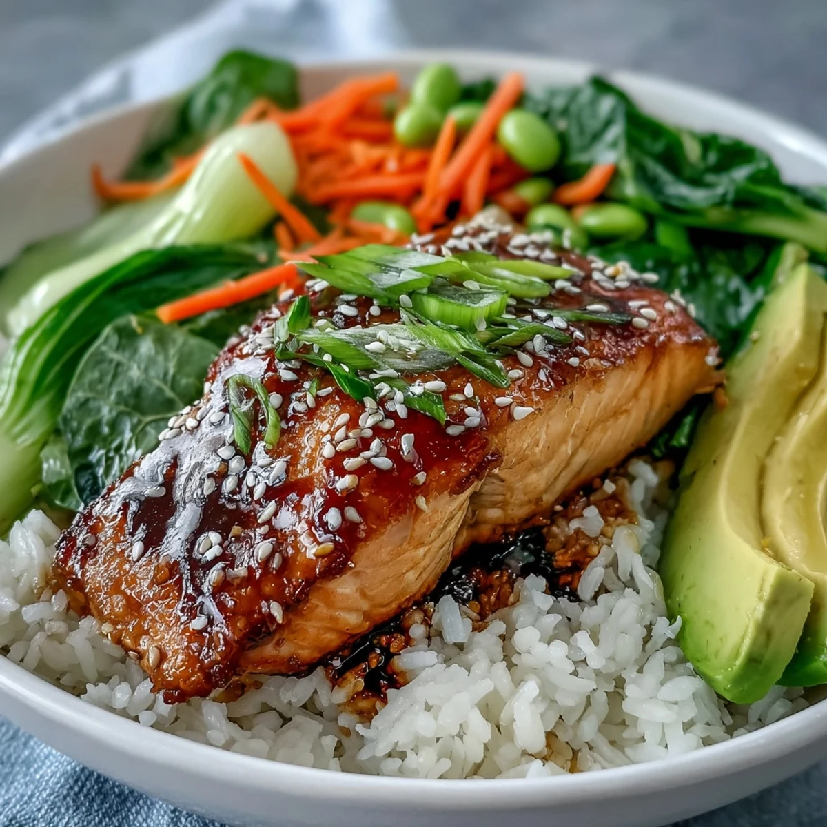 Tender soy ginger salmon fillet served over steamed jasmine rice and stir-fried Asian veggies in a colorful, healthy bowl.