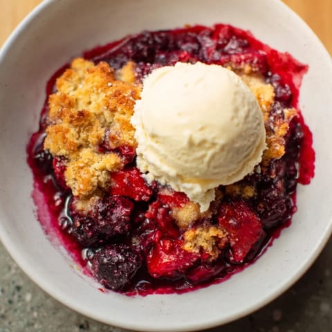 A close-up of a Rustic Summer Berry Cobbler with a buttery topping; imagine the sweet berry aroma.