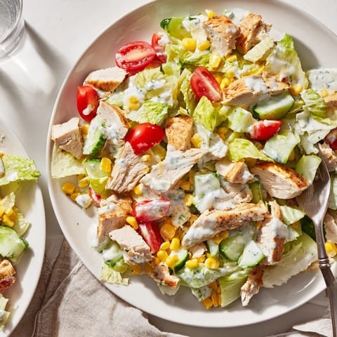 A close-up of the creamy Greek yogurt ranch dressing being drizzled over the hearty, colorful salad ingredients.