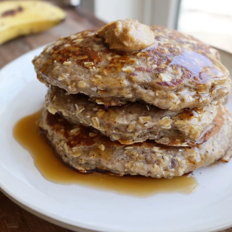 Warm stack of homemade banana oat pancakes, featuring a delightful, inviting texture and a sweet aroma.